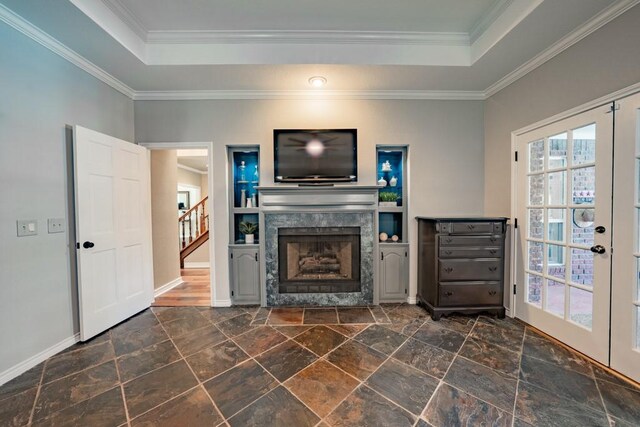 unfurnished living room featuring dark tile patterned floors, a raised ceiling, ornamental molding, and french doors