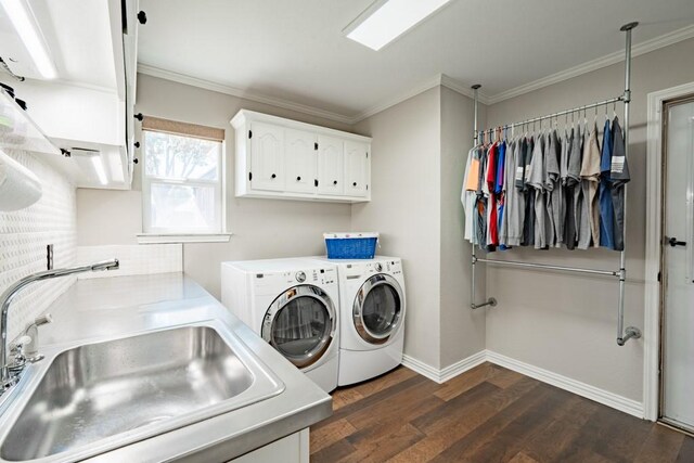 washroom with dark wood-type flooring, cabinets, ornamental molding, washer and clothes dryer, and sink