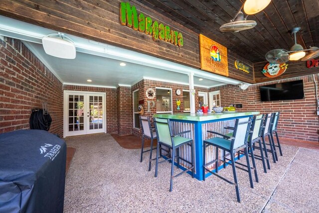 carpeted dining space featuring wooden ceiling, brick wall, and french doors