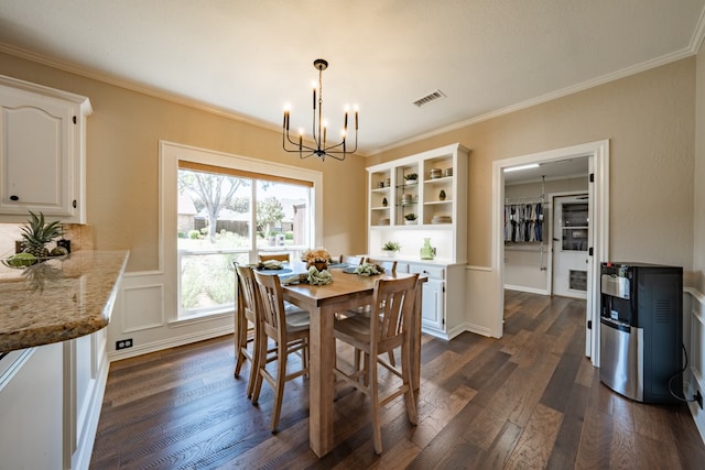 dining space with dark hardwood / wood-style floors, crown molding, and a chandelier