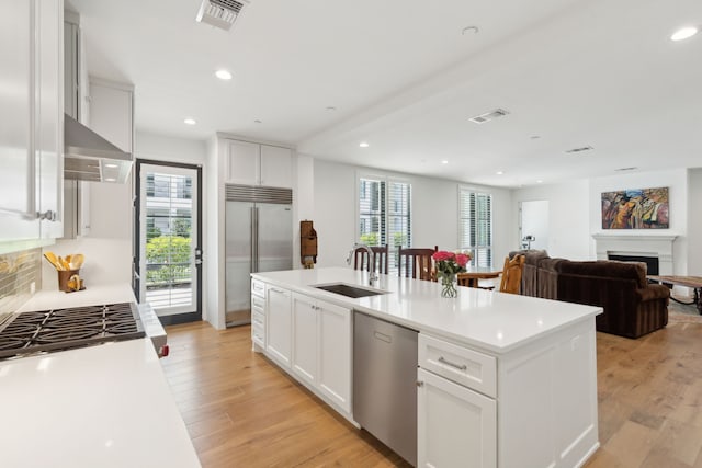 kitchen featuring visible vents, white cabinets, an island with sink, stainless steel appliances, and light countertops