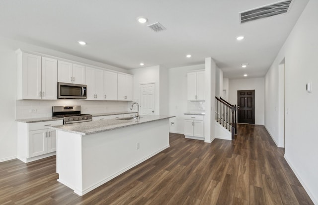 kitchen featuring appliances with stainless steel finishes, dark wood-type flooring, sink, white cabinets, and an island with sink