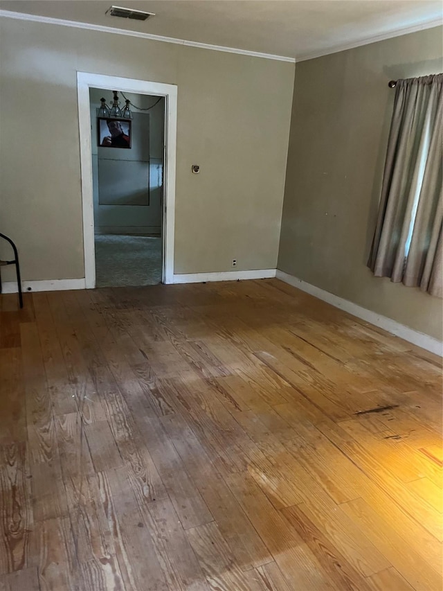 empty room with hardwood / wood-style floors and crown molding