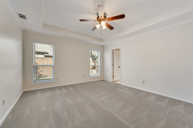 unfurnished room featuring a tray ceiling, carpet flooring, ceiling fan, and crown molding