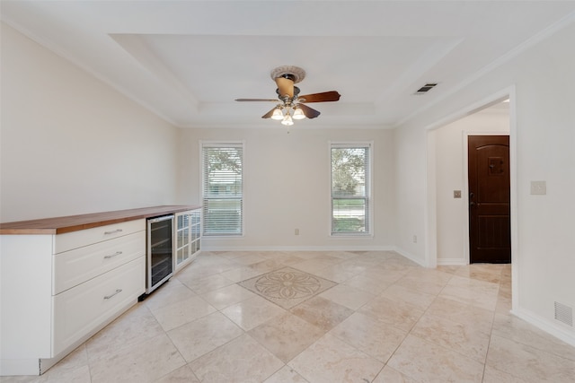 interior space featuring ceiling fan, light tile patterned flooring, a tray ceiling, and beverage cooler