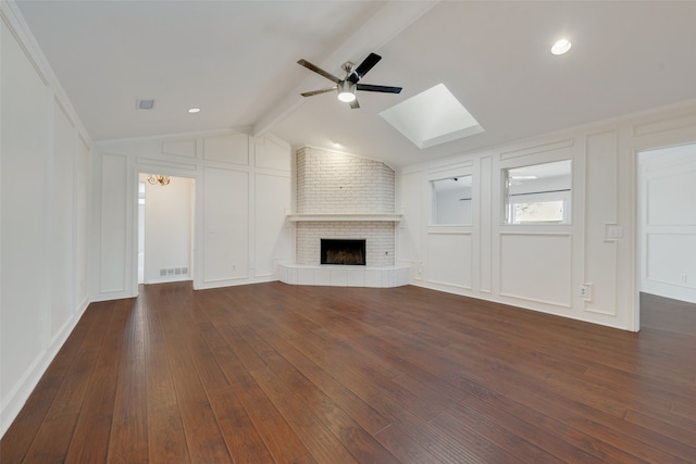 unfurnished living room with ceiling fan, a brick fireplace, brick wall, and dark hardwood / wood-style flooring