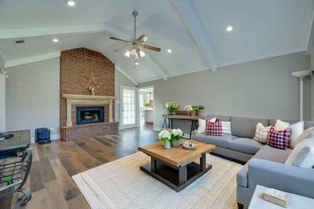 living room with ceiling fan, a brick fireplace, wood-type flooring, and vaulted ceiling