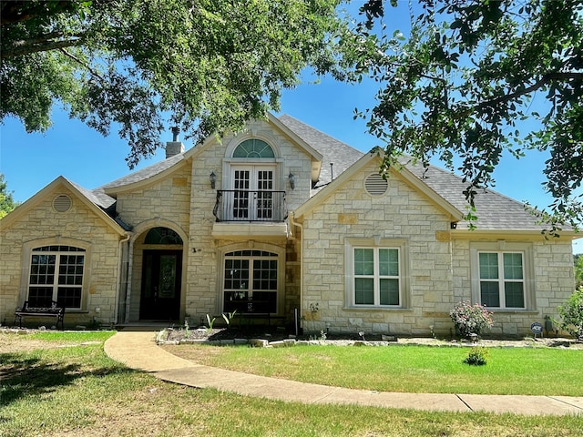 view of front facade featuring a balcony and a front yard