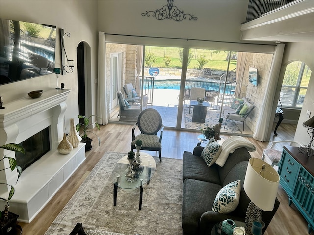 living room featuring a tile fireplace, light hardwood / wood-style flooring, and a towering ceiling