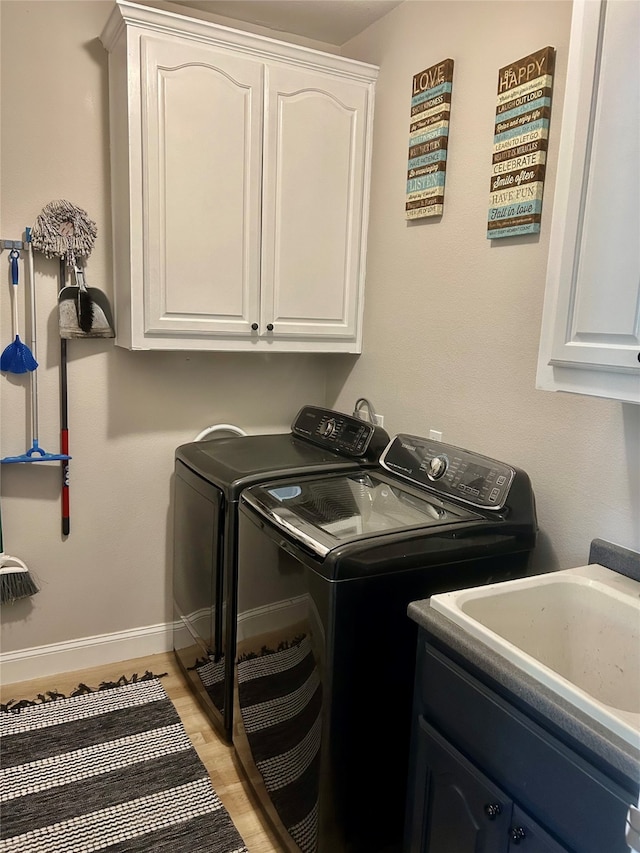 washroom featuring sink, cabinets, light hardwood / wood-style flooring, and washing machine and clothes dryer