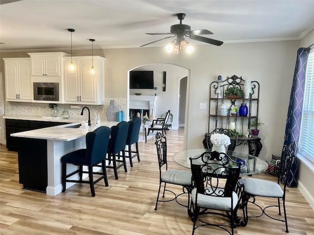 dining space featuring sink, ornamental molding, ceiling fan, and light hardwood / wood-style floors