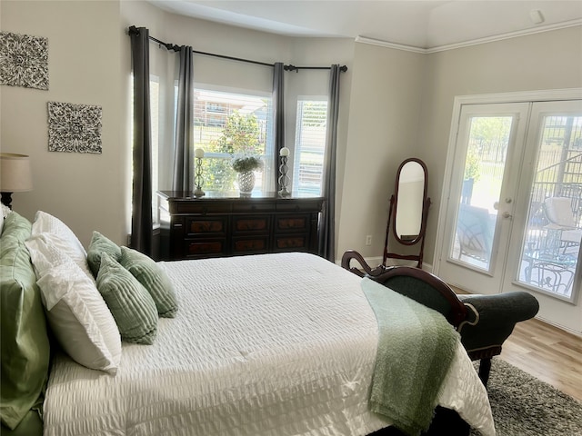 bedroom with access to outside, multiple windows, hardwood / wood-style floors, and french doors