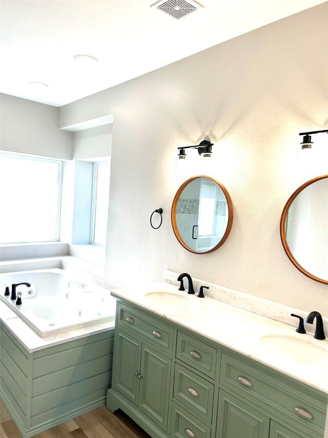 bathroom featuring vanity, wood-type flooring, and tiled bath