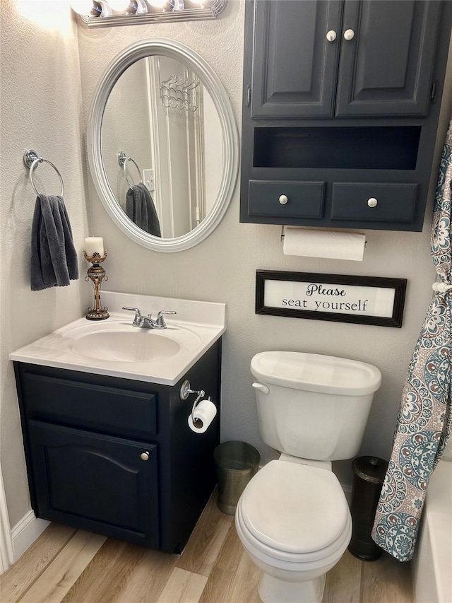 bathroom with toilet, hardwood / wood-style flooring, curtained shower, and vanity