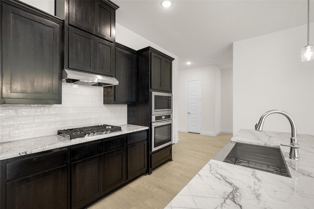 kitchen featuring backsplash, stainless steel gas stovetop, pendant lighting, light hardwood / wood-style floors, and sink