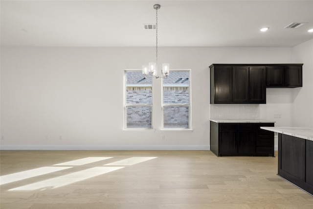 kitchen with light hardwood / wood-style flooring, light stone countertops, a chandelier, and pendant lighting