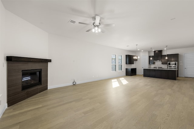 unfurnished living room featuring light hardwood / wood-style flooring, a fireplace, and ceiling fan