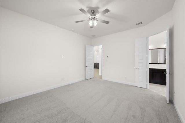 unfurnished bedroom featuring light colored carpet, ceiling fan, and ensuite bath