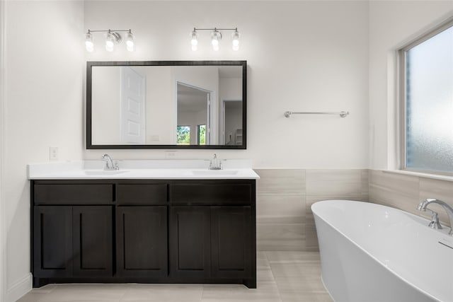 bathroom with tile walls, vanity, a tub, and tile patterned flooring