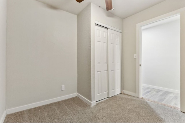 unfurnished bedroom with ceiling fan, light colored carpet, and a closet