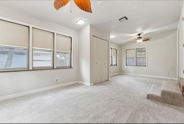 empty room featuring ceiling fan and light colored carpet