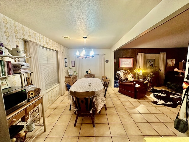 dining area with a textured ceiling, a notable chandelier, and light tile patterned flooring