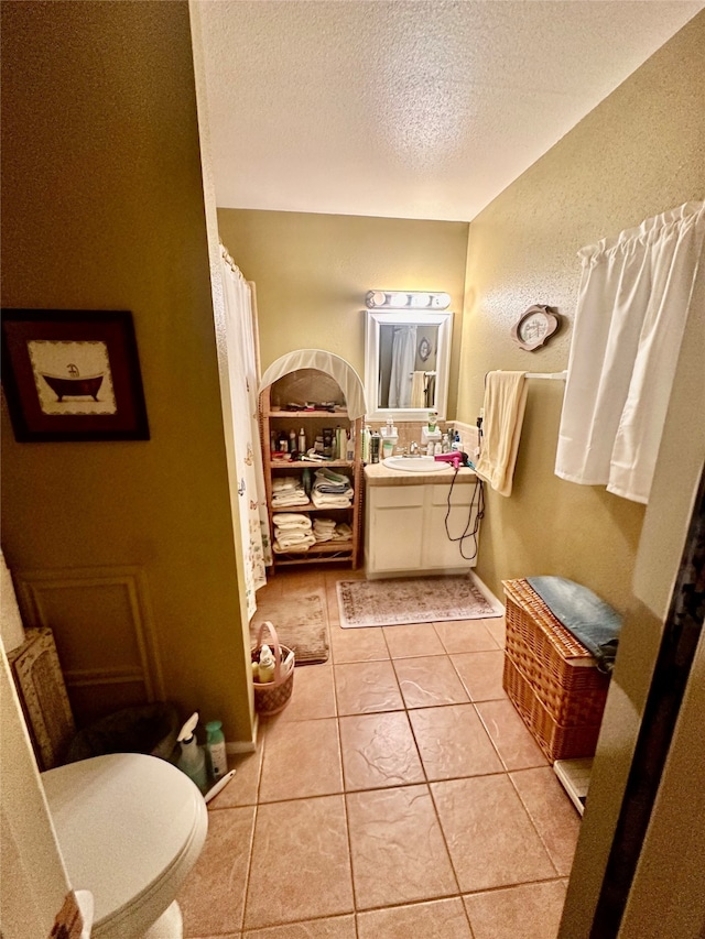 bathroom featuring tile patterned flooring, toilet, a textured ceiling, and vanity