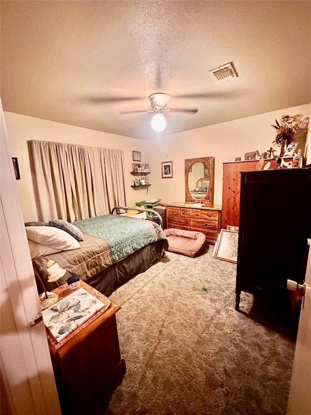 carpeted bedroom featuring ceiling fan and a textured ceiling