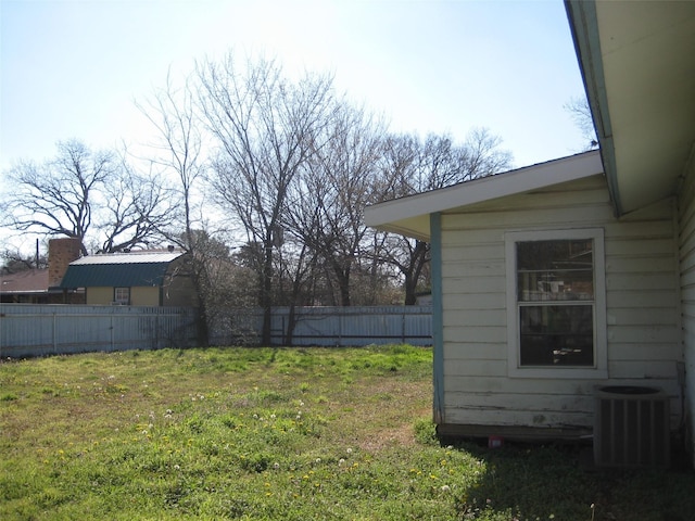 view of yard featuring central AC and fence