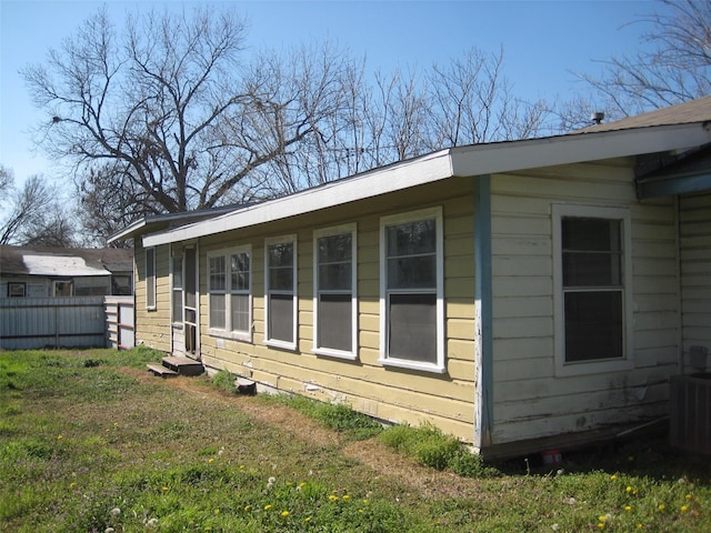 view of property exterior featuring central AC unit, a yard, and fence