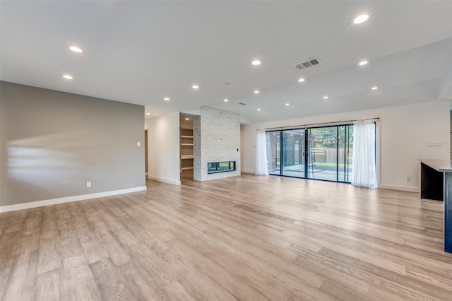 unfurnished living room featuring a stone fireplace and light hardwood / wood-style flooring