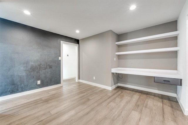 unfurnished room featuring built in desk and light hardwood / wood-style floors