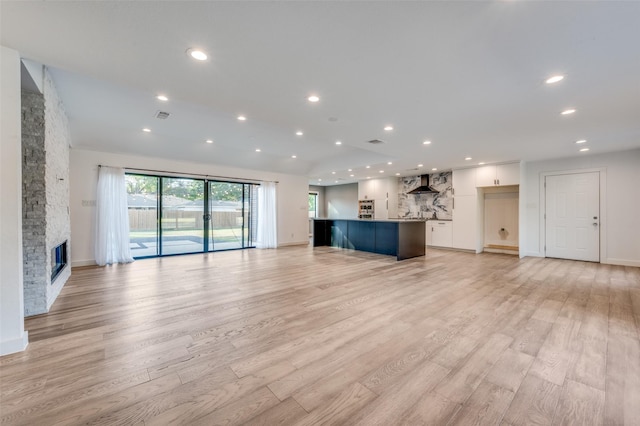 unfurnished living room featuring a stone fireplace and light wood-type flooring