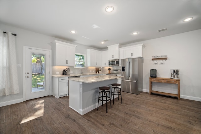 kitchen featuring tasteful backsplash, white cabinetry, dark wood-type flooring, and stainless steel appliances