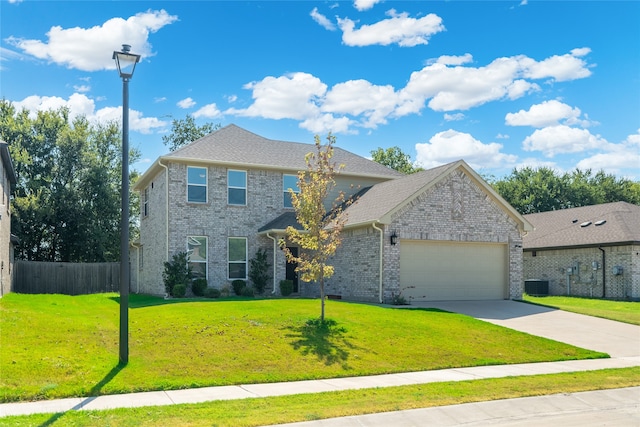 view of front of house featuring cooling unit, a garage, and a front yard