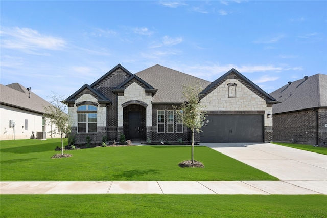 french provincial home featuring a front yard and a garage