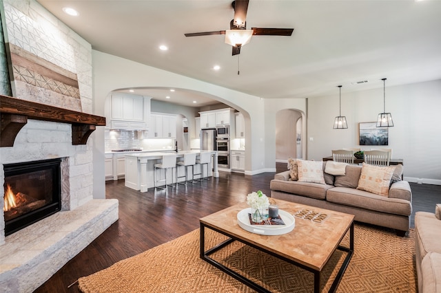 living room with dark hardwood / wood-style flooring, a fireplace, and ceiling fan