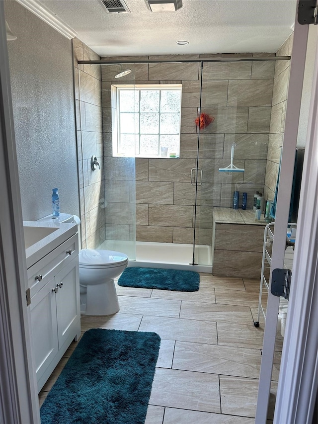 bathroom with tile patterned floors, a shower with shower door, a textured ceiling, vanity, and toilet