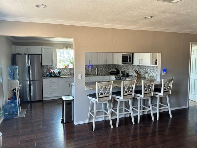 kitchen with appliances with stainless steel finishes, tasteful backsplash, and dark hardwood / wood-style floors