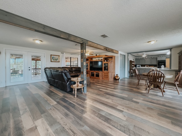 living room with light hardwood / wood-style floors, a textured ceiling, ceiling fan, and wooden walls