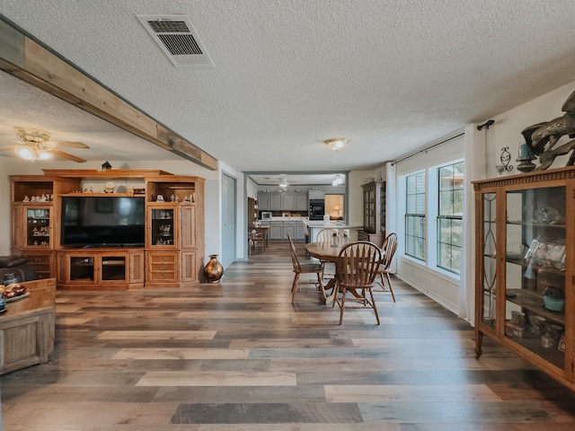 living room with a textured ceiling, light hardwood / wood-style flooring, ornamental molding, ceiling fan, and wooden walls