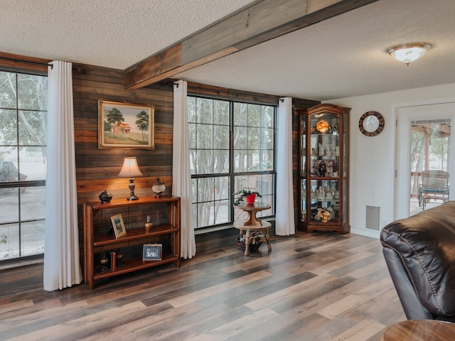 living room with wooden walls, crown molding, light hardwood / wood-style floors, ceiling fan, and a textured ceiling