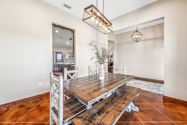 dining space featuring dark tile patterned flooring and ceiling fan with notable chandelier