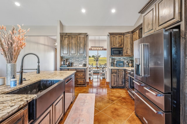 kitchen featuring light stone countertops, appliances with stainless steel finishes, tasteful backsplash, and sink