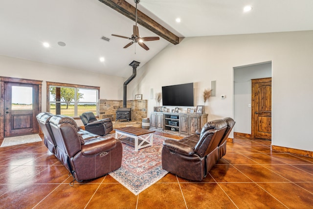 living room with ceiling fan, dark tile patterned floors, beam ceiling, a wood stove, and high vaulted ceiling