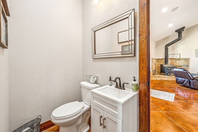 bathroom featuring vanity, tasteful backsplash, a wood stove, tile patterned floors, and toilet