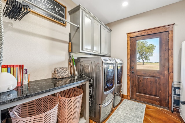 laundry room with washing machine and clothes dryer, cabinets, and dark tile patterned floors