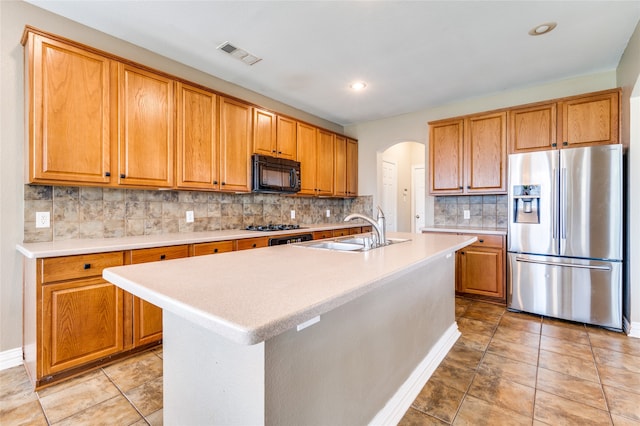 kitchen with decorative backsplash, black appliances, sink, and an island with sink