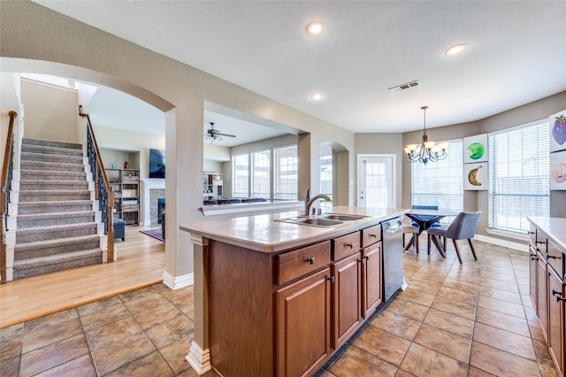 kitchen featuring a wealth of natural light, a center island with sink, sink, and decorative light fixtures