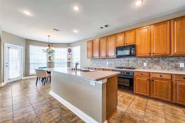 kitchen featuring a center island with sink, decorative backsplash, black appliances, sink, and decorative light fixtures